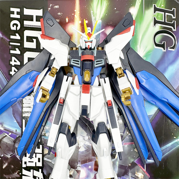 Gundam Strike Freedom actionfigur foran fargerik bakgrunn med vinger, vist på produktside.
