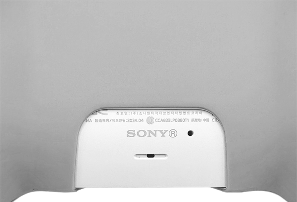 Detaljbilde av baksiden på en hvit PS5 controller, viser Sony-logoen og serienummer.