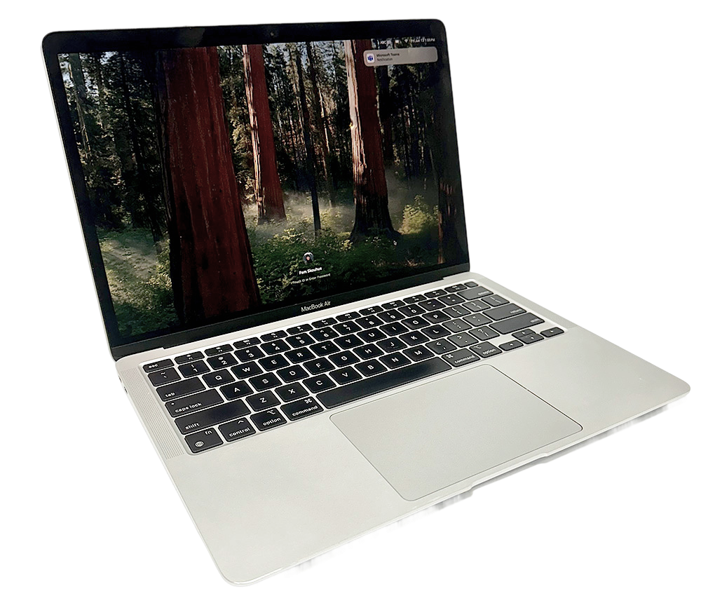 Hopea värinen computer mac air, avattuna ja näytöllä metsätaustakuva, tuotekuvassa.