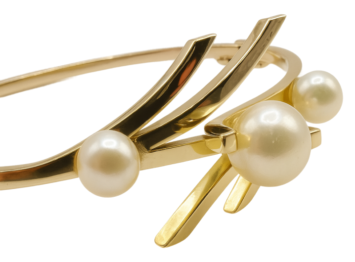 Gold bangle bracelet featuring three round white pearls on a modern, sculptural design.
