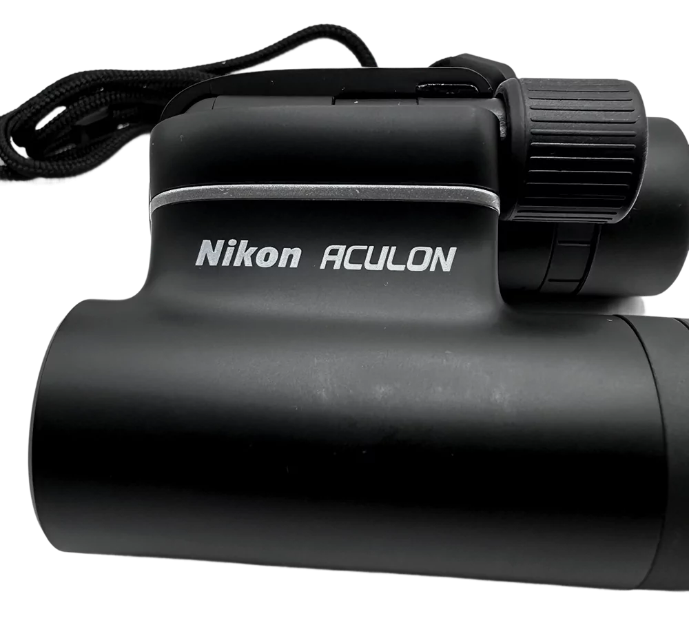 Prismáticos Nikon Aculon T01 en color negro, diseño compacto y portátil con correa para transportarlo.