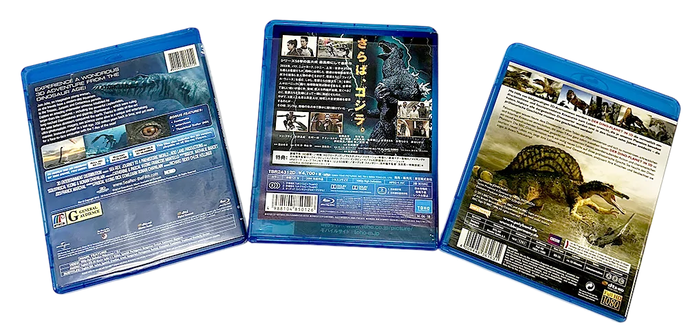 Three Dinosaur Blu-ray cases showing detailed back covers with images of prehistoric creatures and movie information.