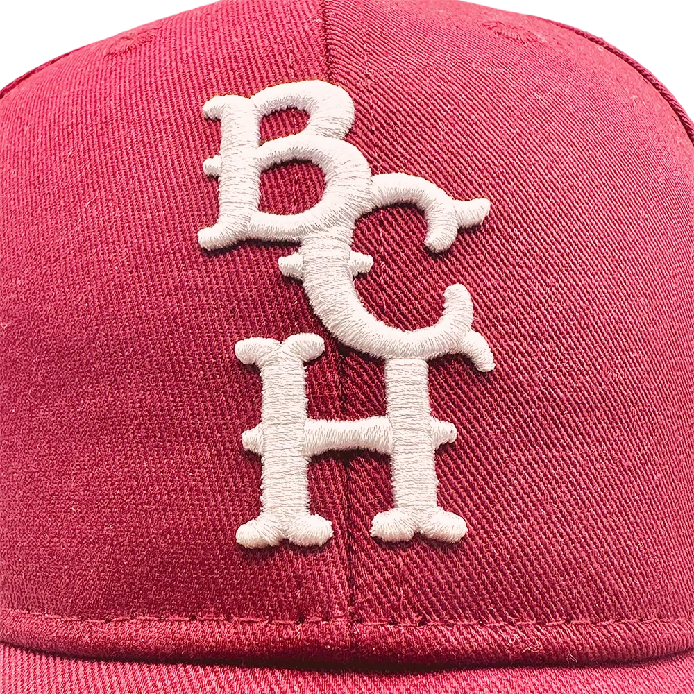 Rød Bench Baseballkasket med hvide, broderede bogstaver "BCH" på fronten.
