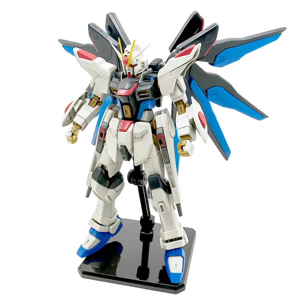 Figura Gundam Strike Freedom na postolju, s plavo-crnim krilima i detaljima u bijeloj, crvenoj i zlatnoj boji.
