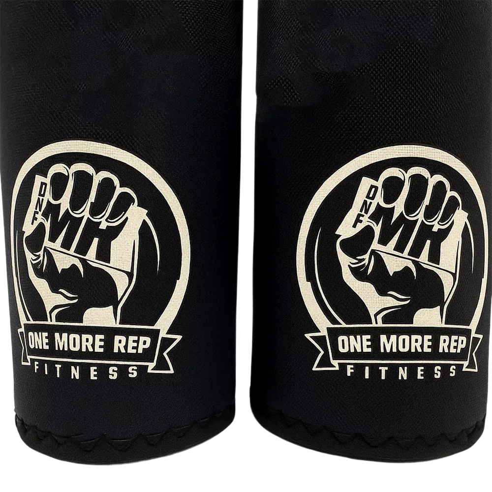 Close-up of One More Rep Fitness Kneepads featuring a fist logo and brand name on black fabric.