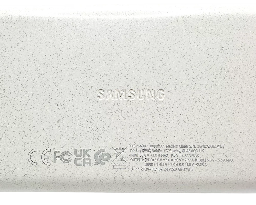 Samsung Varavirtalähde, valkoinen pinta ja tekniset merkinnät näkyvissä tuotteen takapuolella.