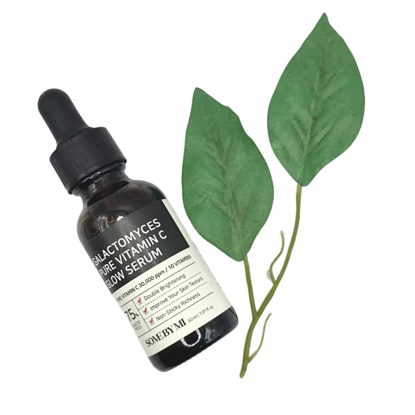 Botol serum Some By Mi Vitamin C bersama dua helai daun hijau sebagai hiasan.