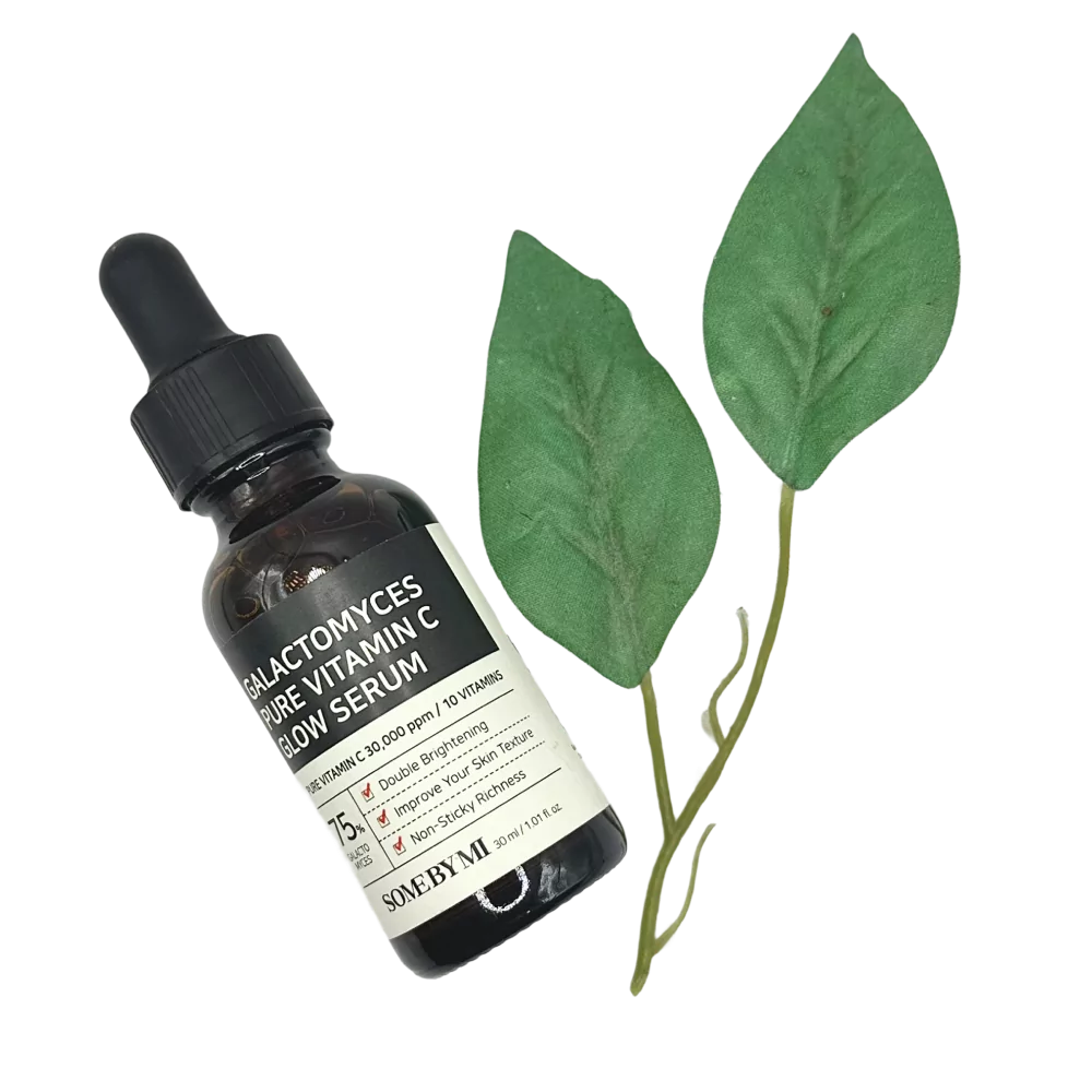 Botol serum Some By Mi Vitamin C bersama dua helai daun hijau sebagai hiasan.