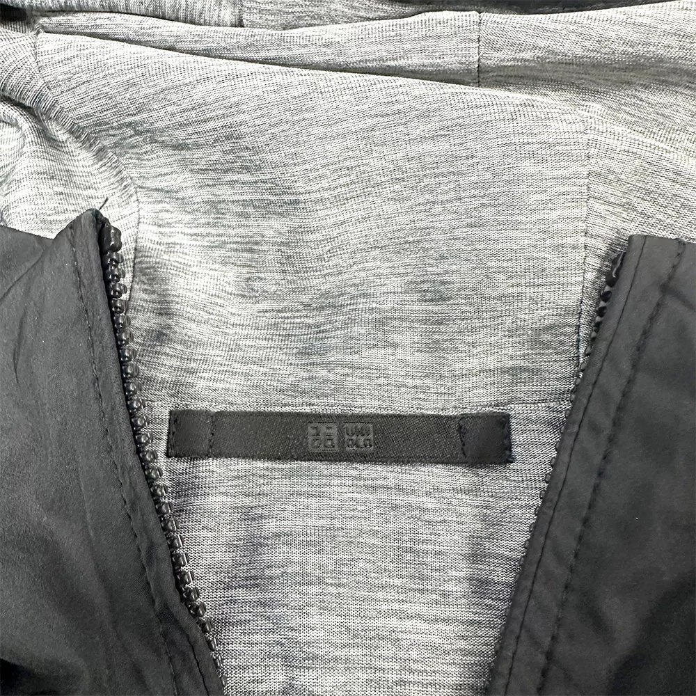 Dettaglio interno della Uniqlo Parka Reversibile, tessuto grigio chiaro e logo Uniqlo sull’etichetta.