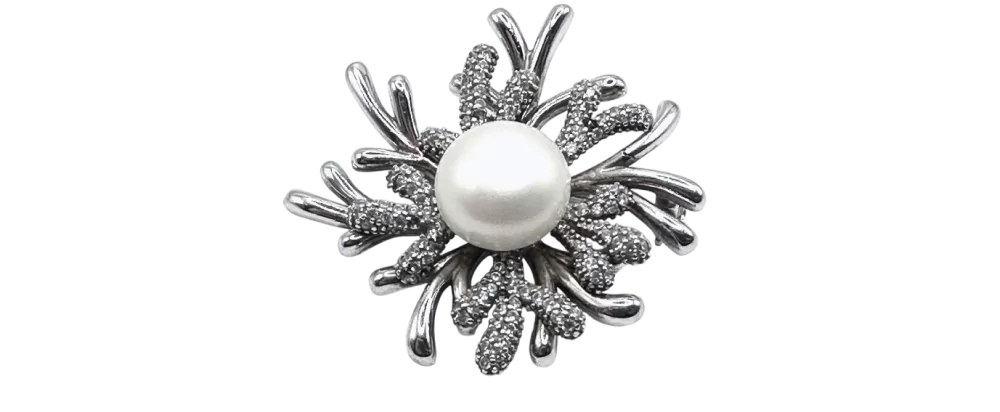 Srebrna broša s koraljnim detaljem i bisernom sredinom na bijeloj pozadini.