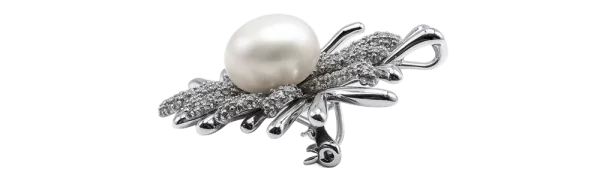 Srebrna broša s koraljnim detaljem, ukrašena biserom i finim metalnim uzorkom.