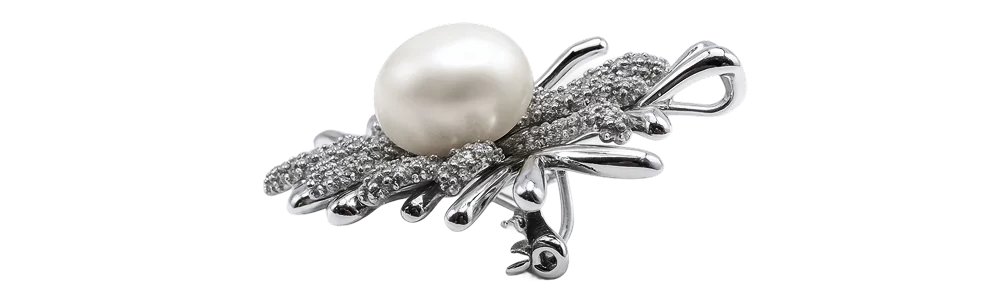 Srebrna broša s koraljnim detaljem, ukrašena biserom i finim metalnim uzorkom.