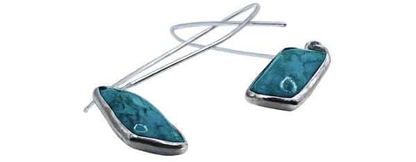 Stříbrné visací náušnice s tyrkysovými kameny na bílém pozadí.