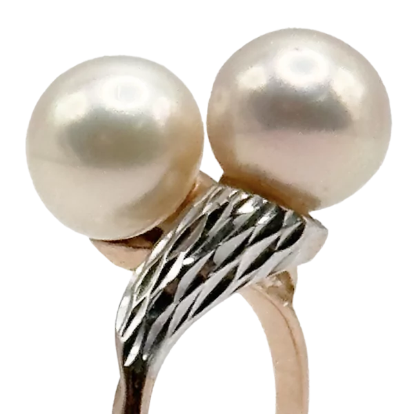 Zlati prstan z dvema biseroma in srebrnim okrasjem, prikazan za prodajo.