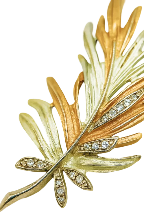 Two-tone gold leaf brooch with sparkling crystals, featuring intricate details and elegant design.