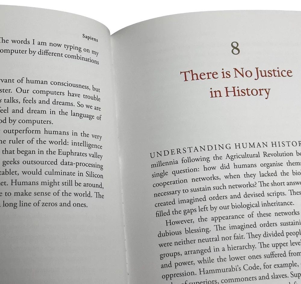 Livro aberto na página 8 de "Sapiens", com o título "There is No Justice in History" em destaque.